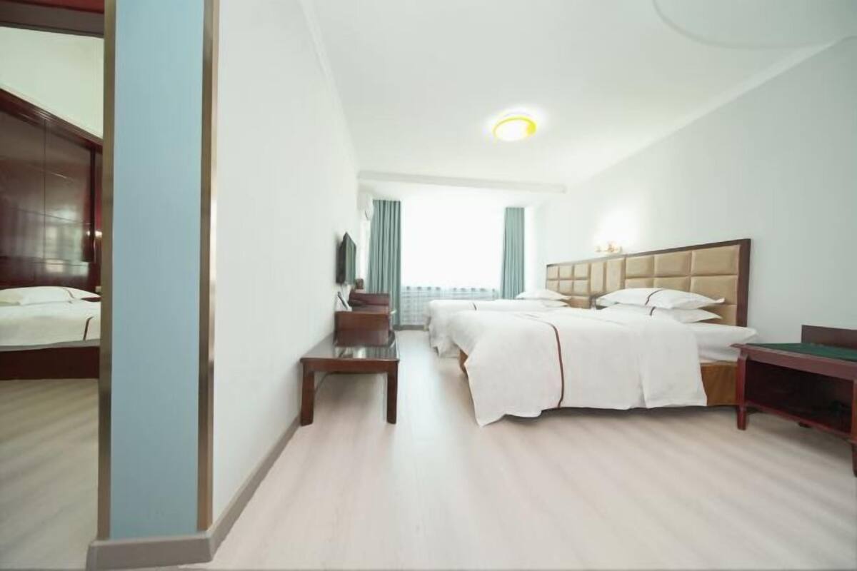 Una camera d'albergo con un letto, comodini, una scrivania e vista sulla città.