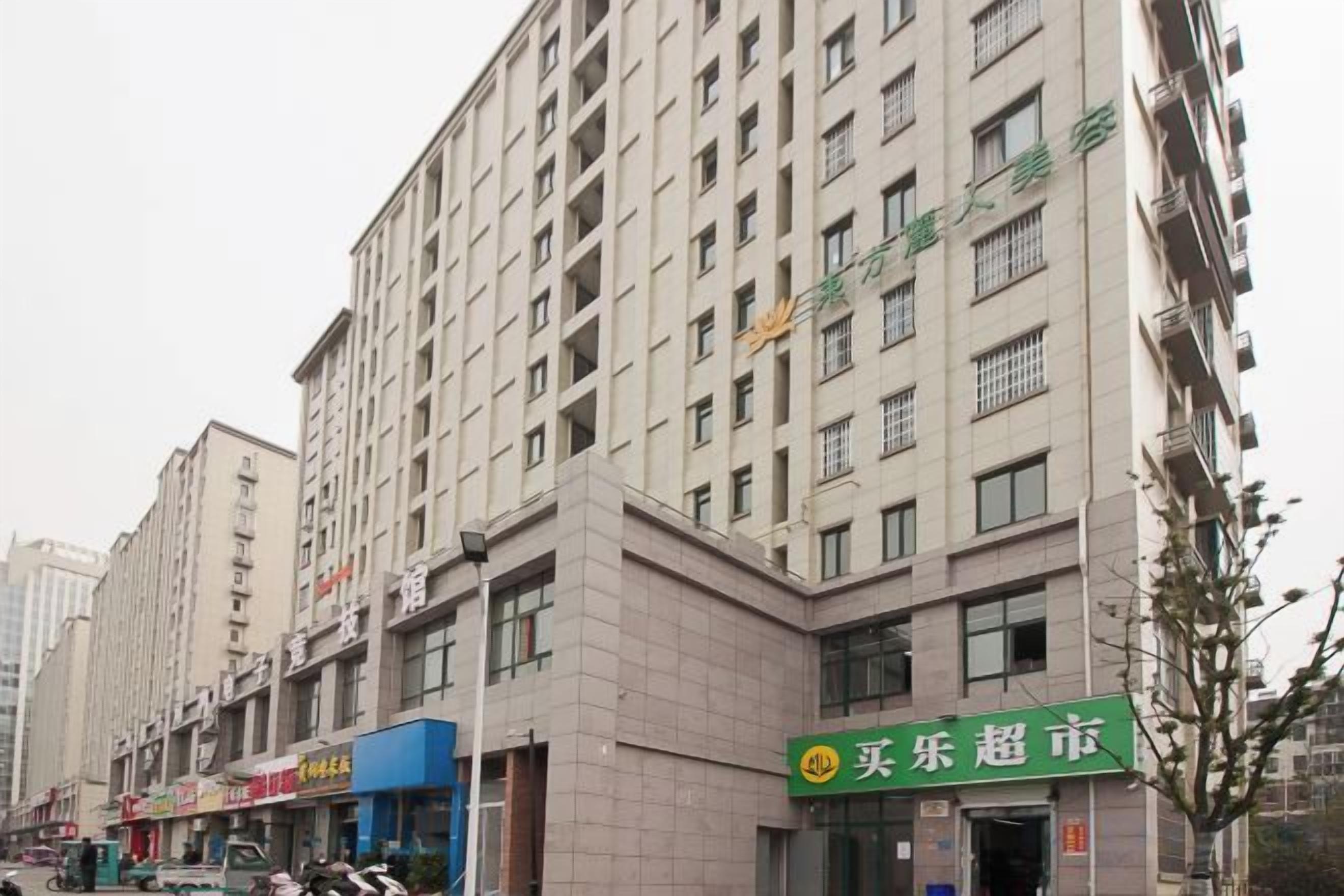 A multi-story building with a commercial ground floor, featuring a green sign with white text, and a clear sky above.