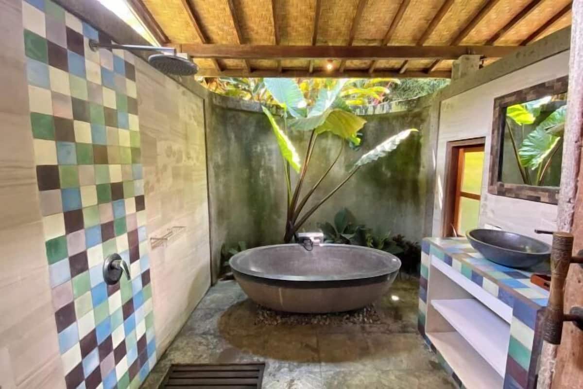 Een badkamer met een betegelde muur in ruitpatroon, een ruim bad en een douchehoek.