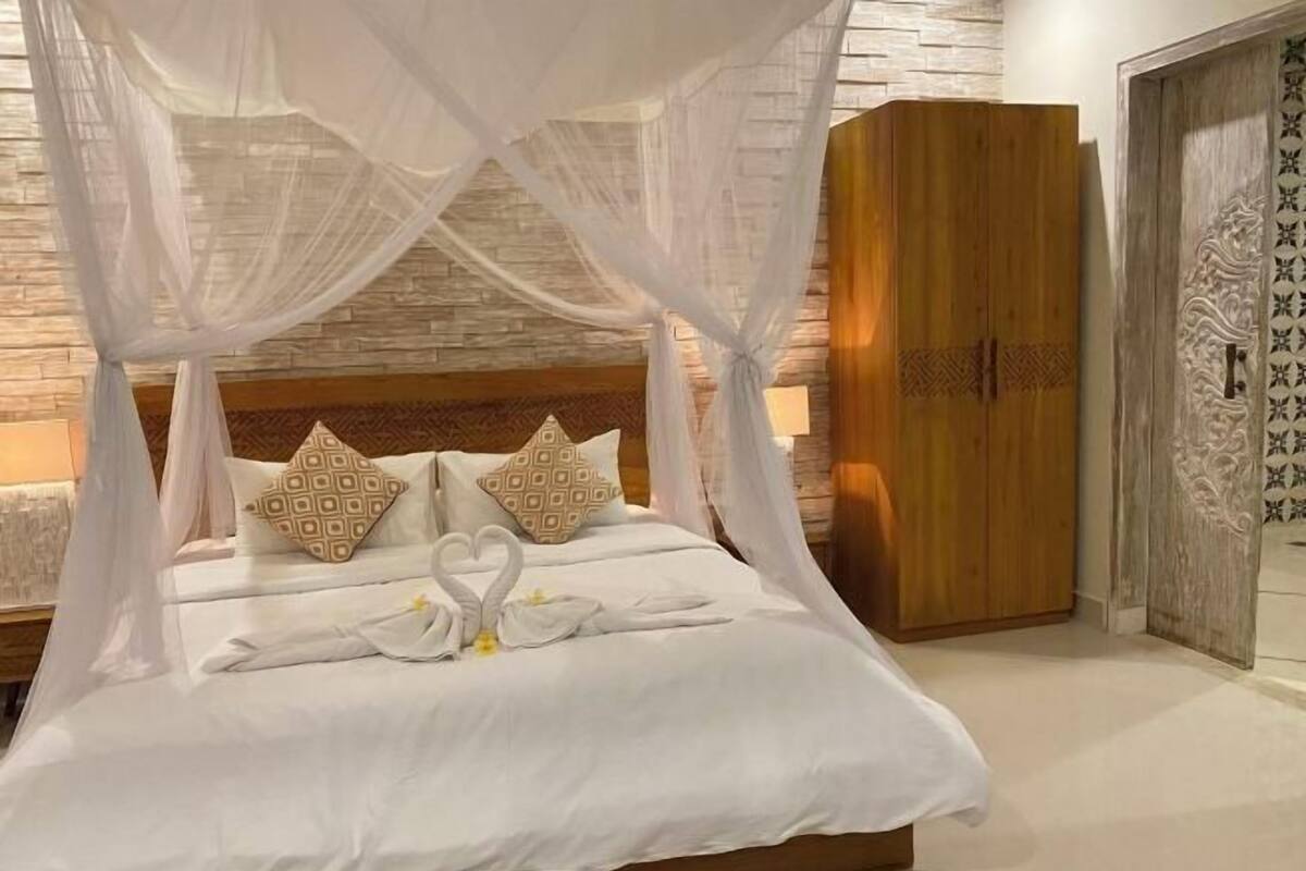 Een bed met hemelbed, kussens en een zwaan decoratie.