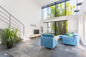 A modern living room with a large window, a staircase, and a potted plant. - Boao Canal Village Resort (Qionghai)