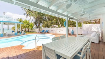 Relax by the pool surrounded by palm trees and a shaded gazebo.