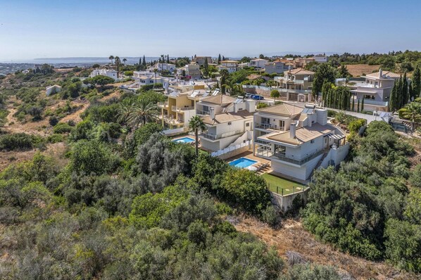 A residential area with modern houses, a swimming pool, and a view of the coastline.