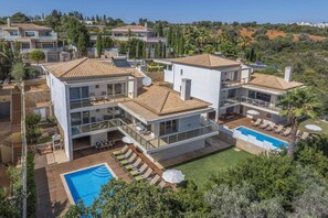 Une villa à plusieurs étages dotée d’une piscine, d’un espace extérieur aménagé et offrant une vue sur le paysage environnant.