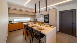 Una cocina moderna con una isla central, electrodomésticos integrados y una puerta oscura.