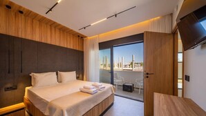 Una habitación de hotel moderna con una cama grande, un balcón con vistas y un televisor de pantalla plana.