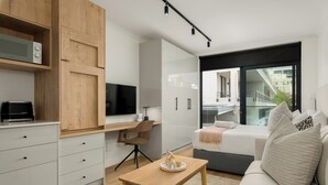 A modern living room with a sofa, a wooden table, and a TV. - The Sage l Studio l Courtyard Access (Cape Town)