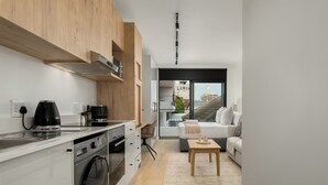 A modern kitchen with a washing machine, a coffee maker, and wooden cabinets. - The Sage l Studio l Courtyard Access (Cape Town)