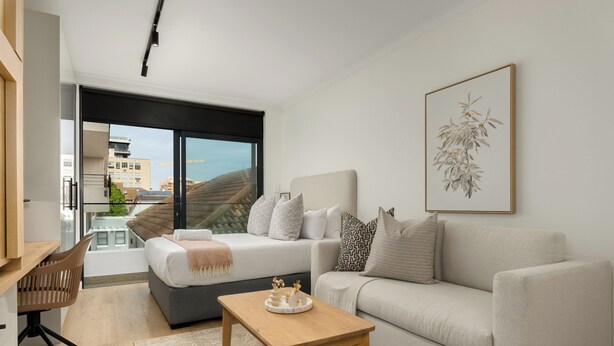 A modern living room with a sofa, a coffee table, and a bed. There is a large window with a view of buildings and hills. - The Sage l Studio l Courtyard Access (Cape Town)