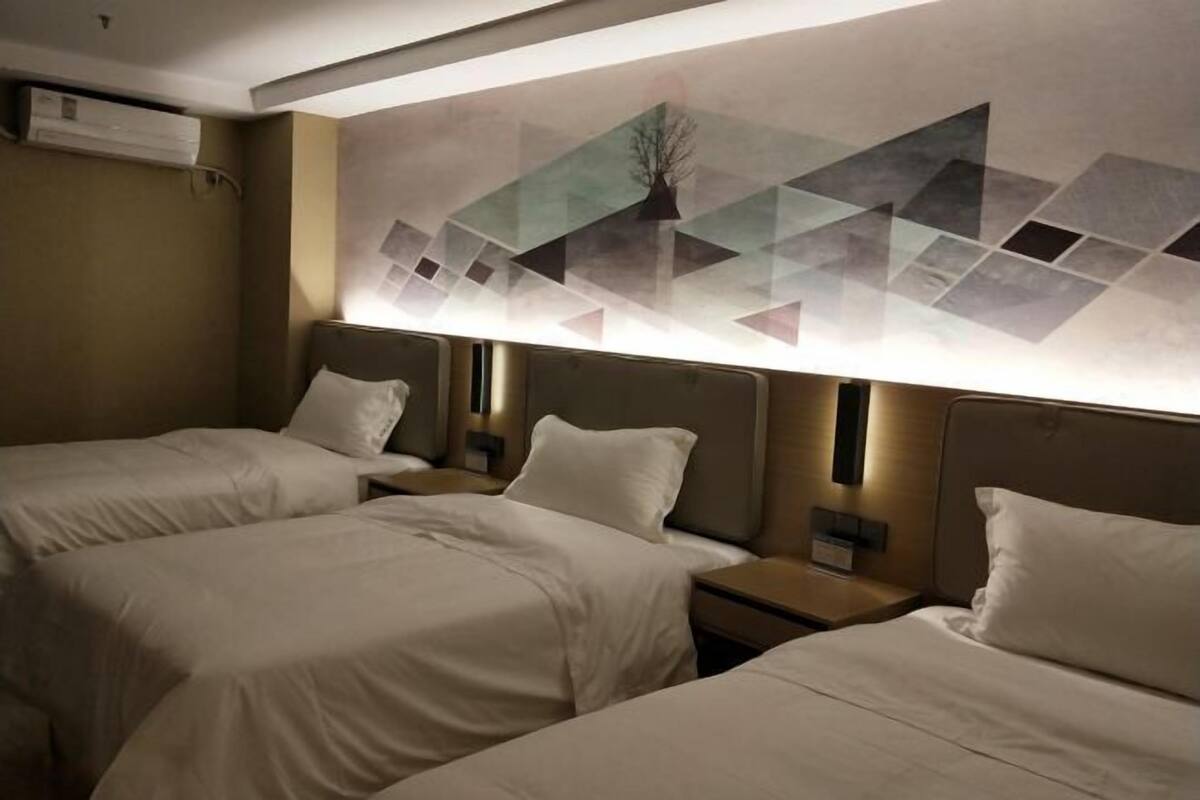A hotel room with two beds, a wall-mounted air conditioner, and a geometric wall art piece.