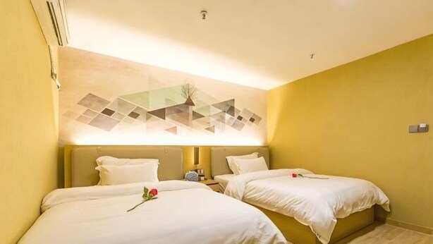 Quarto de hotel com duas camas, uma obra de arte na parede e uma pequena mesa com telefone.