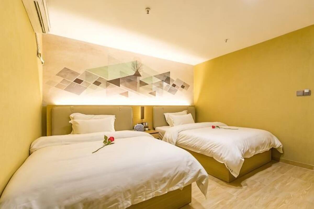 A hotel room with two beds, a wall-mounted artwork, and a small table with a phone.