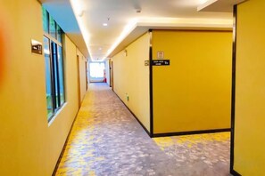 A hotel hallway with a yellow carpet, doors on the right, and a sign indicating a room number. - Yuebei Hotel (Guangzhou)