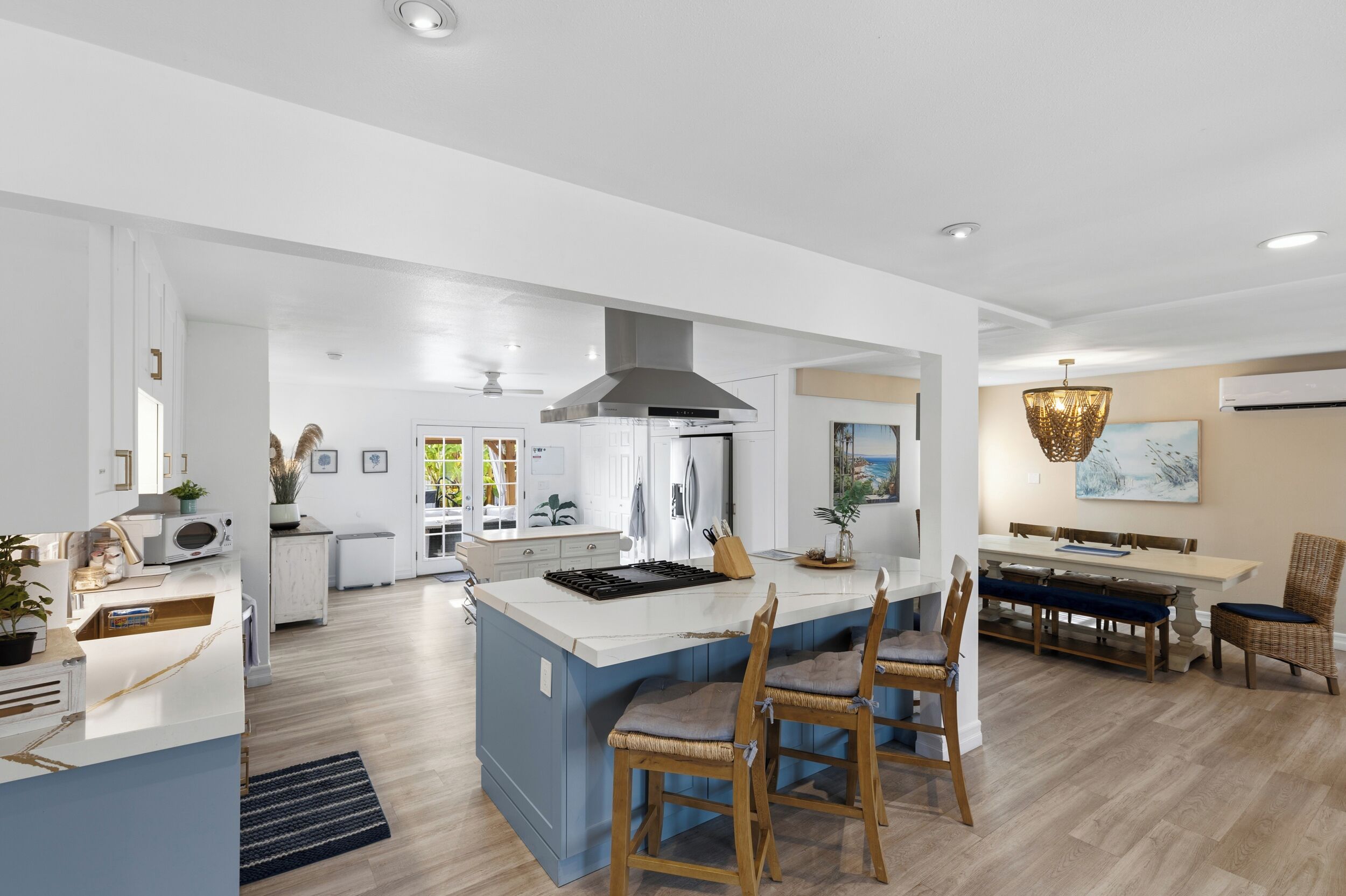 A spacious kitchen with a central island, a dining area with a large table and chairs, and a modern ceiling design.