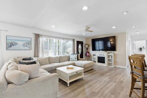 A modern living room with a sectional sofa, a flat-screen TV, and a fireplace.