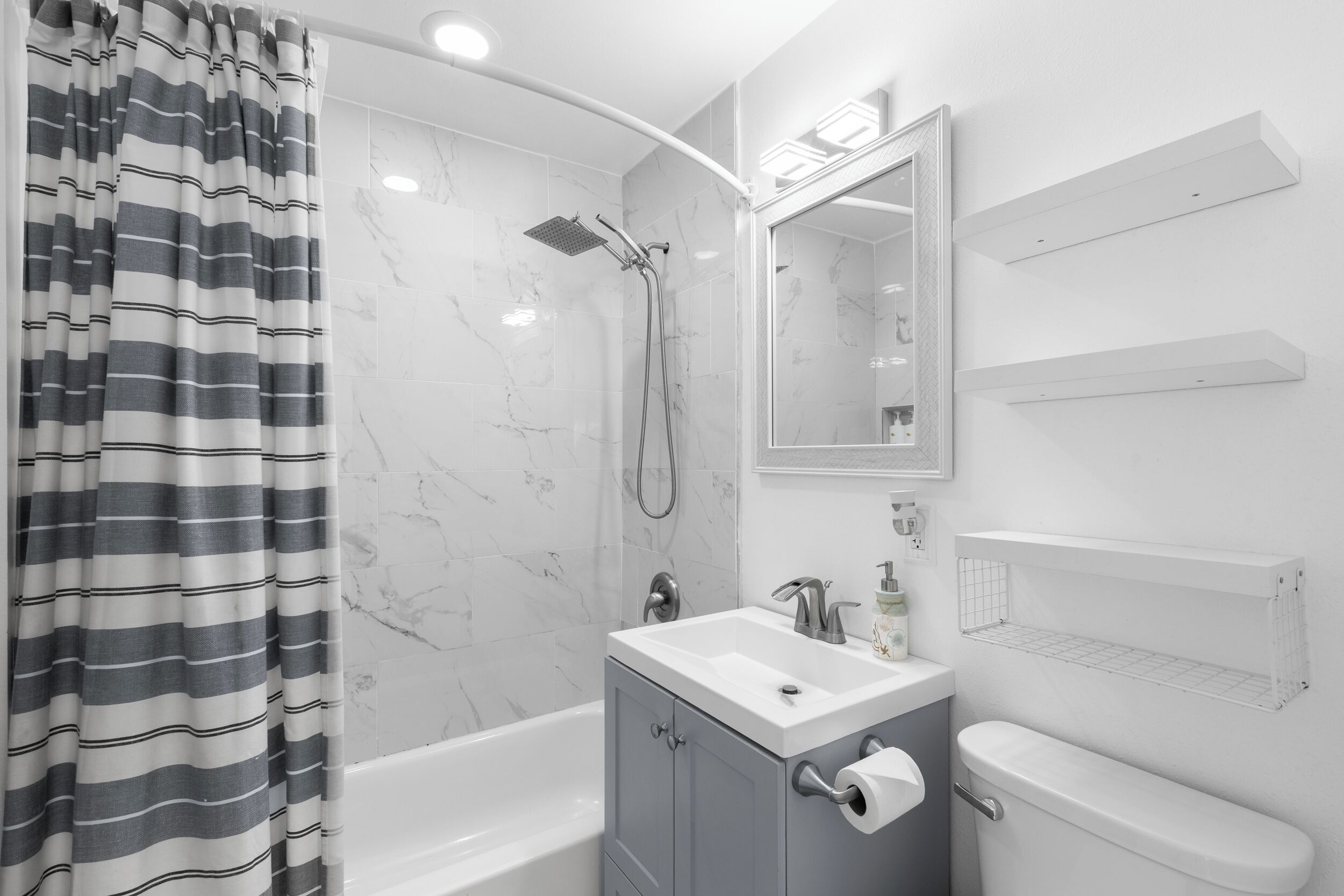 Een moderne badkamer met een bad, douche, wastafel en toilet.