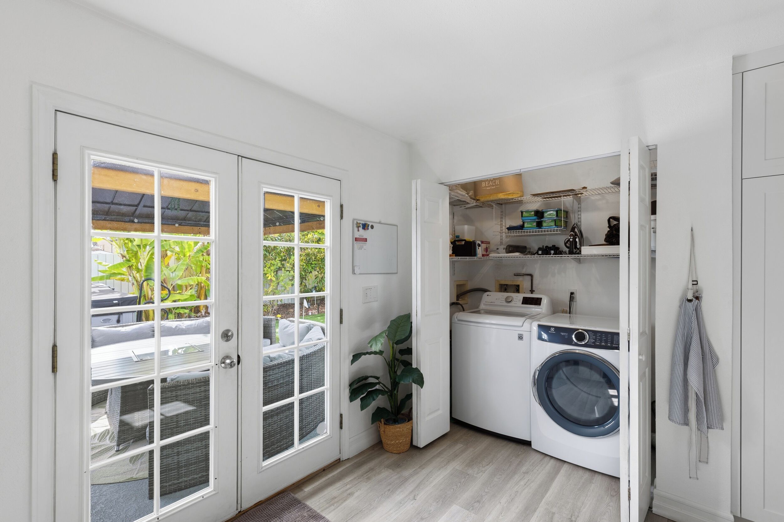 A compact laundry room with a washing machine, dryer, and shelves for storage.