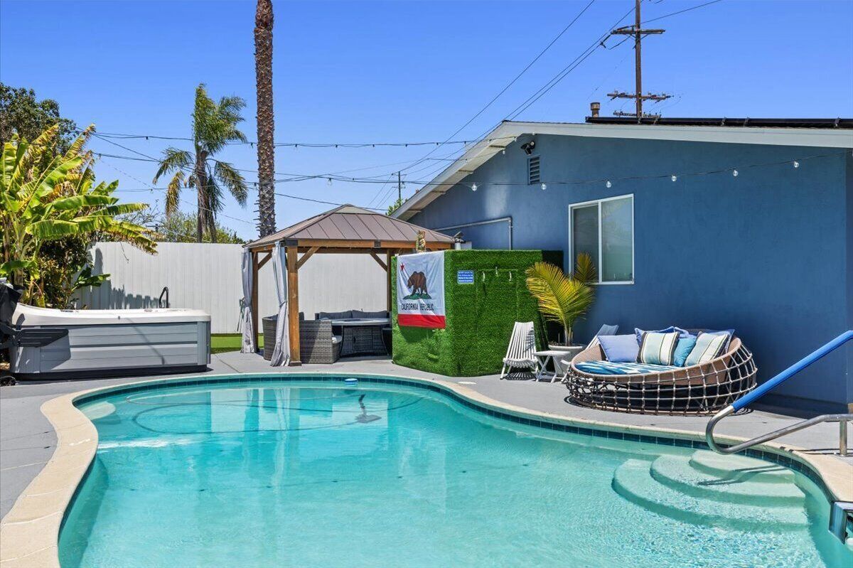 A swimming pool with a hot tub, lounge chairs, and a small gazebo.