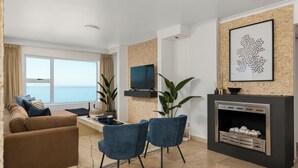 Una sala de estar moderna con un sofá, dos sillones, un televisor, una chimenea y un ventanal con vistas.