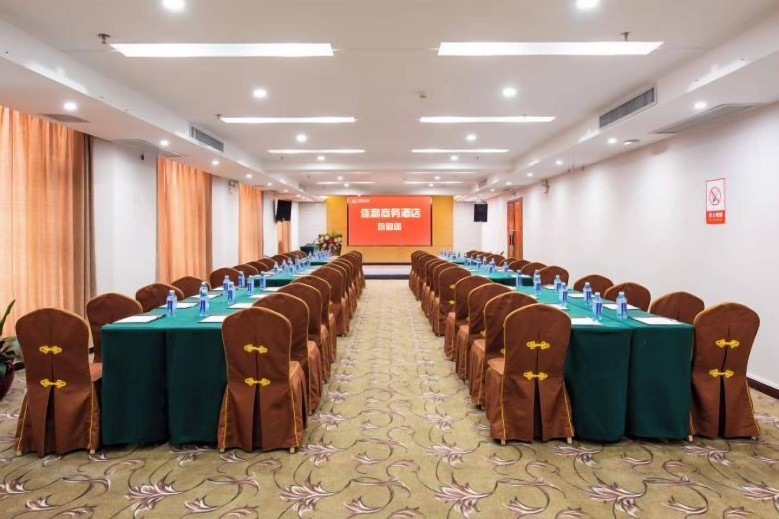A conference room with long tables, chairs, and a presentation screen.
