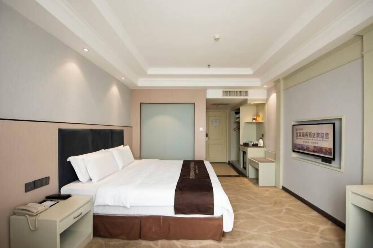 Een hotelkamer met een bed, nachtkastje en een televisie aan de muur.