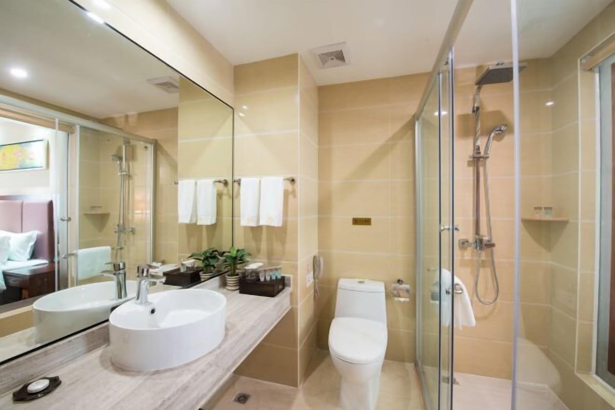 A modern bathroom with a glass-enclosed shower, a white sink, and a toilet.