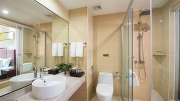 A modern bathroom with a glass-enclosed shower, a white sink, and a toilet.