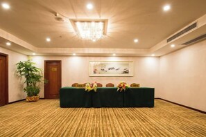 A conference room with a carpeted floor, a table with chairs, a chandelier, a framed artwork on the wall, and a potted plant. - Jiagao Business Hotel(FoShan NanHai WanKe) (Foshan)