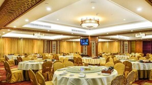A banquet hall with round tables, gold chairs, and a television screen. - Jiagao Business Hotel(FoShan NanHai WanKe) (Foshan)