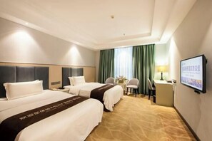 Une chambre d’hôtel avec deux lits, un bureau, une chaise, une télévision et une fenêtre avec des rideaux.