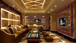 A luxurious lounge area with a large sofa, a coffee table, and a television mounted on the wall. - Jiagao Business Hotel(FoShan NanHai WanKe) (Foshan)
