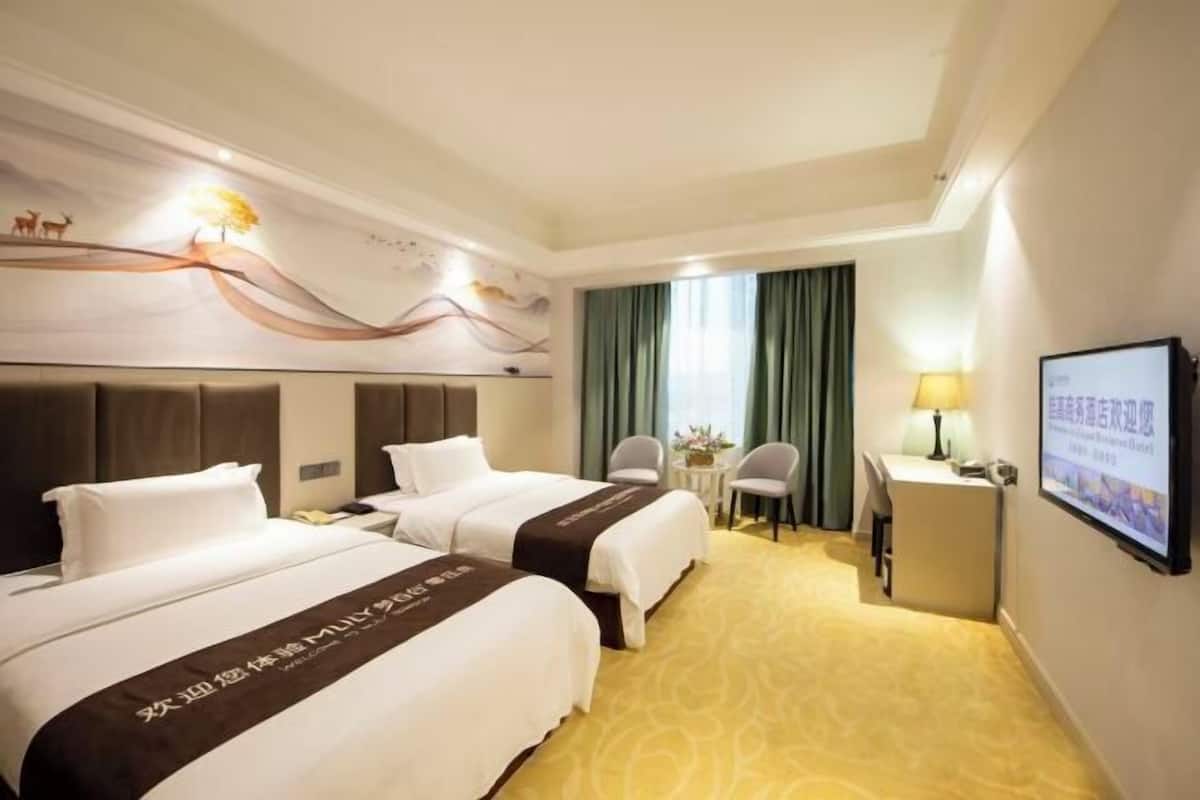 Een hotelkamer met twee bedden, een bureau, een stoel, een televisie en een decoratief muurschildering.