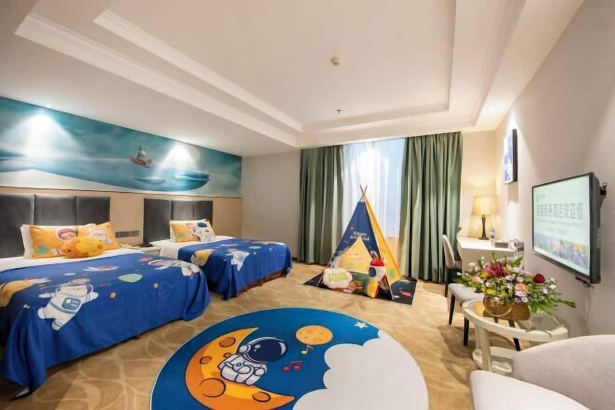 Een hotelkamer met twee bedden, een muurschildering, een tent en een bureau met een lamp.