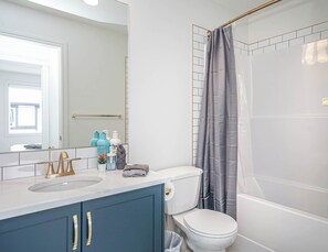 A modern bathroom with a white sink, gold faucets, a blue cabinet, and a white toilet. - NEW Home, Double Car Garage & Close to Airport (Calgary)