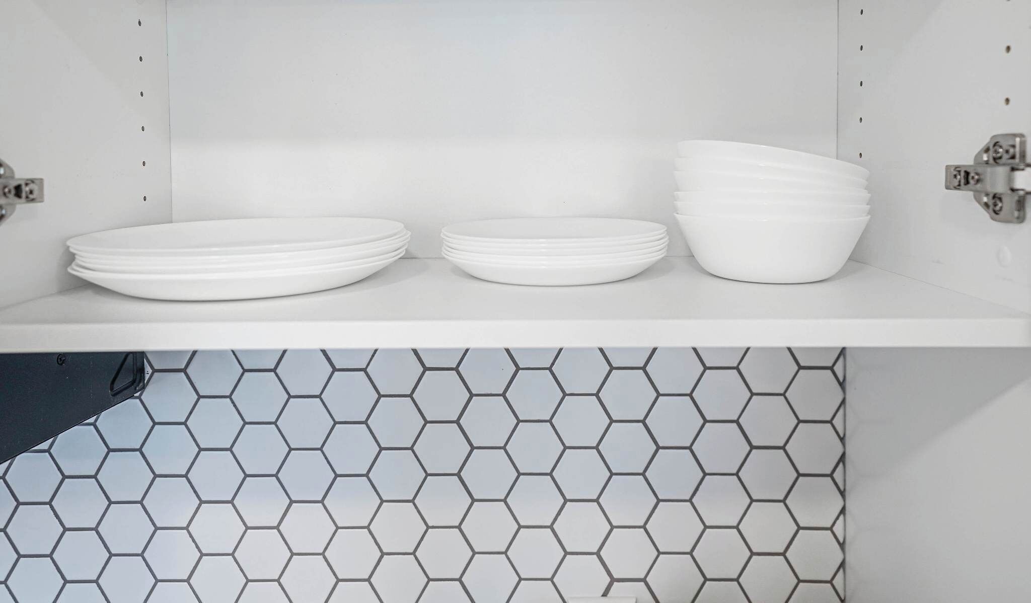 A kitchen shelf with white plates and bowls.