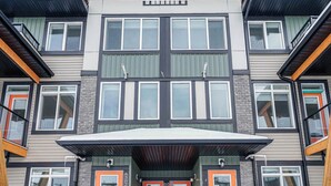A multi-story building with a flat roof, large windows, and a covered entrance. - NEW Home, Double Car Garage & Close to Airport (Calgary)