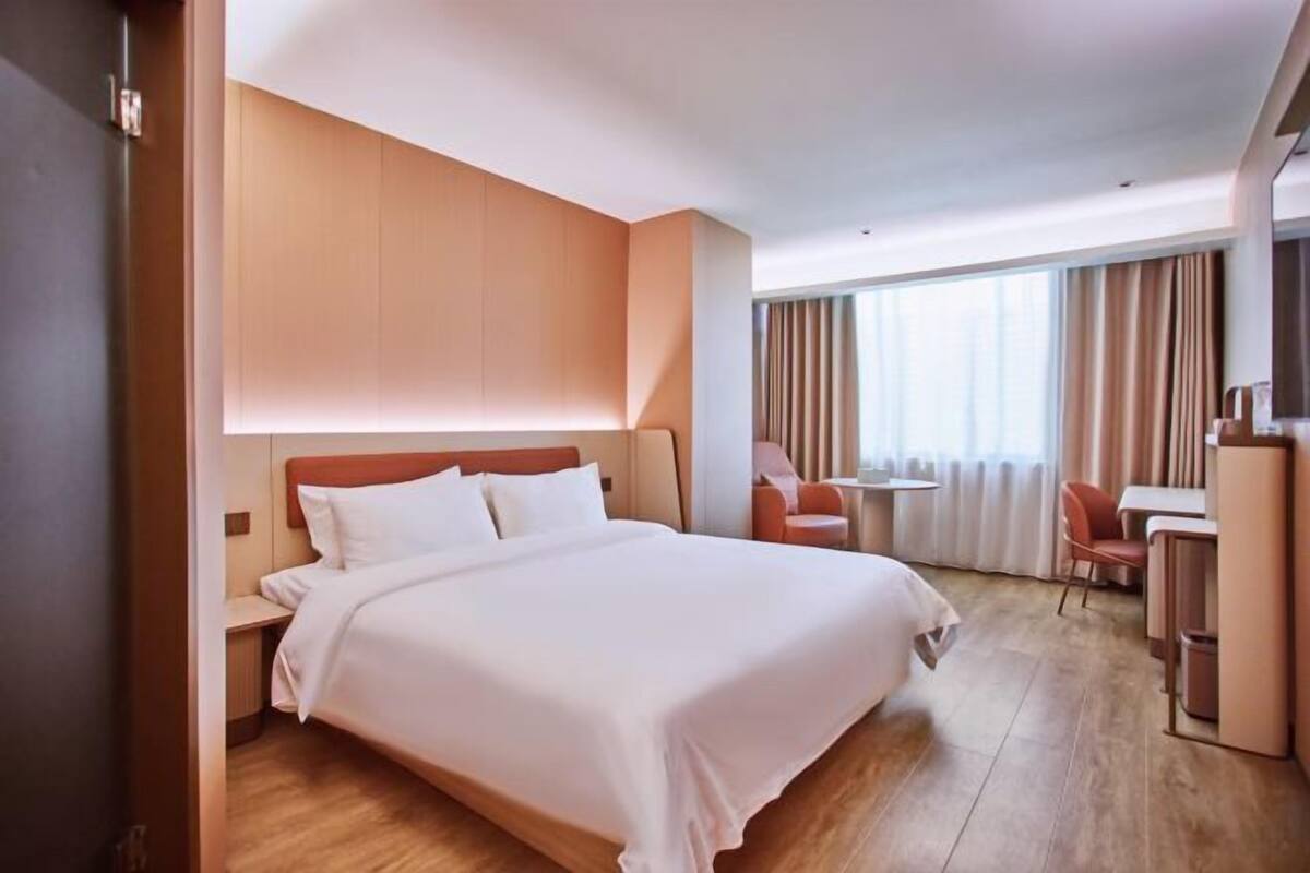 Hotellihuone, jossa on suuri sänky, työpöytä, tuoli ja televisio.