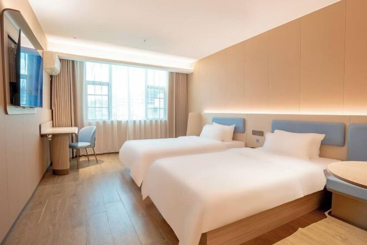 Hotellihuone, jossa on kaksi sänkyä, työpöytä, tuoli ja televisio.
