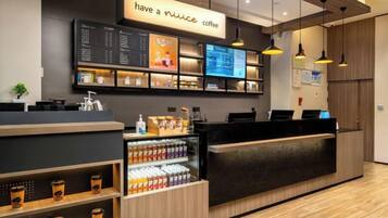 A coffee shop interior with a counter, menu board, and beverage display.