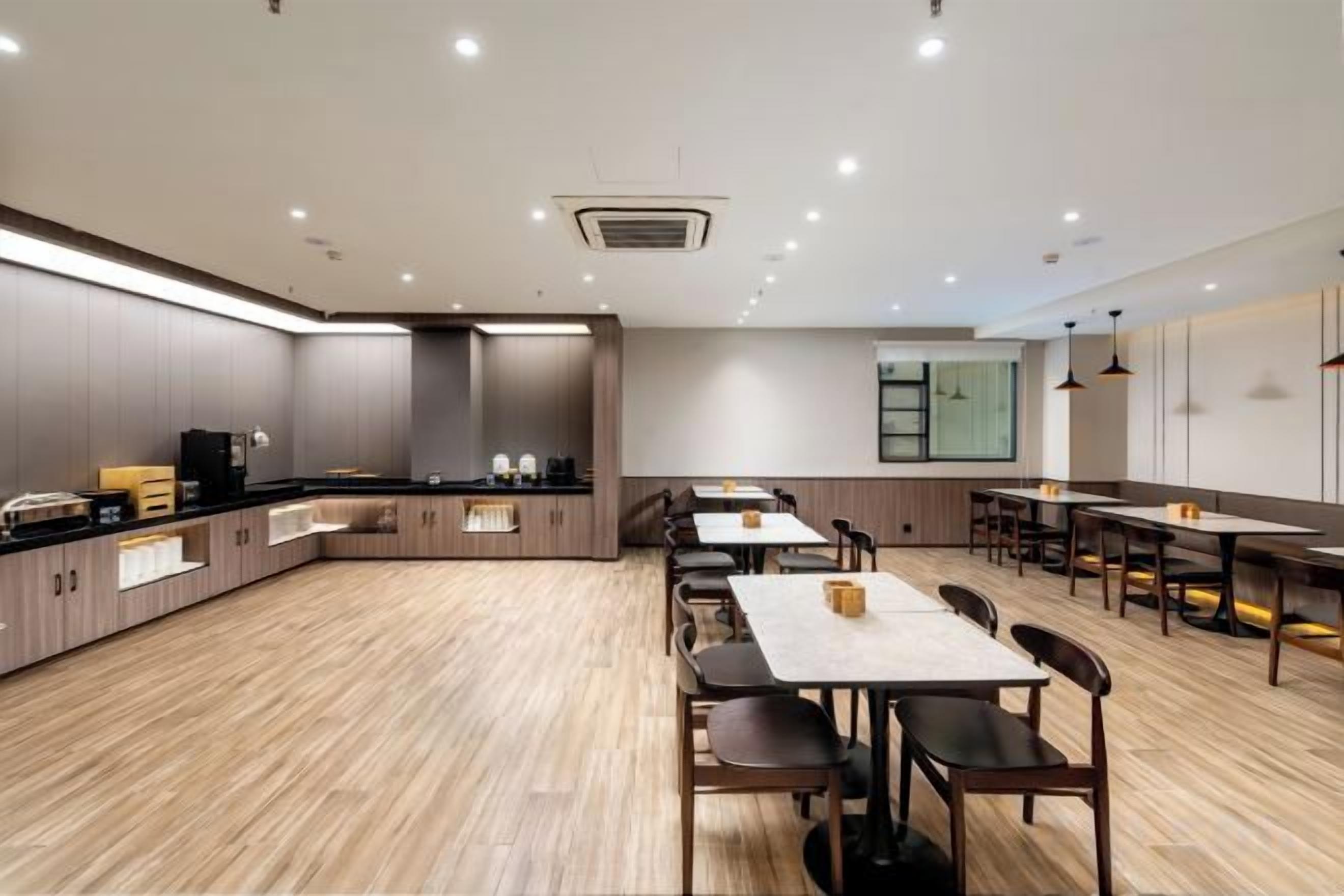A modern dining area with a long counter, multiple tables, and chairs.