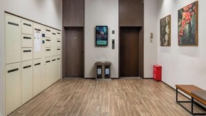 Un hall d’hôtel avec des casiers, une petite table et deux tableaux accrochés au mur.