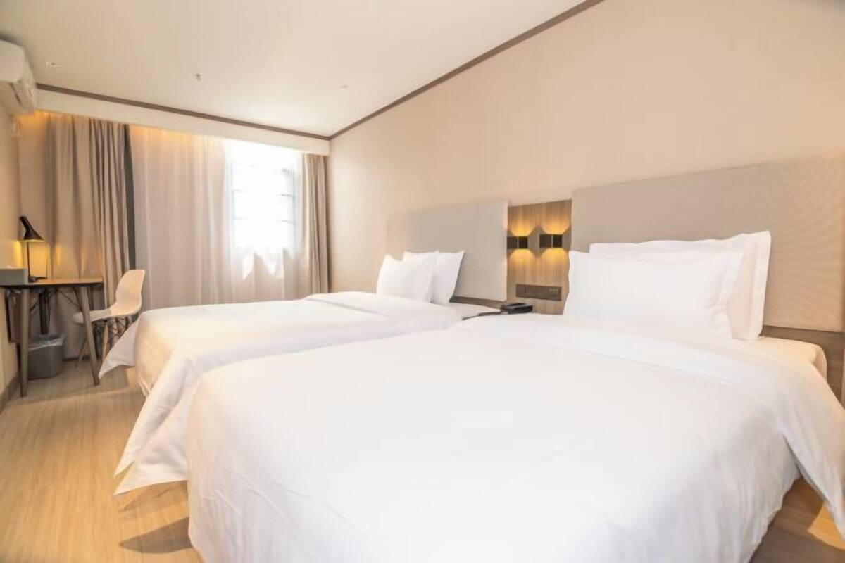 A hotel room with two beds, a desk, and a chair.