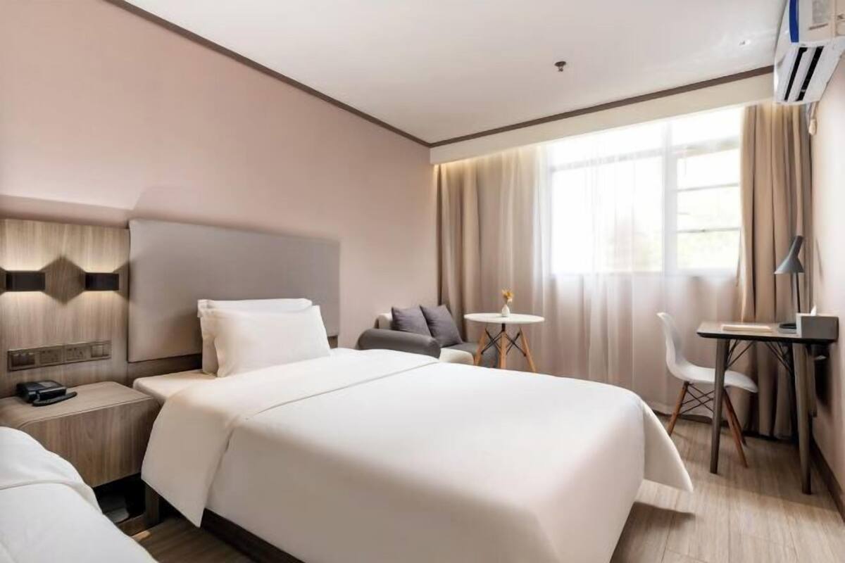 A hotel room with a large bed, bedside tables, a desk, and a chair.