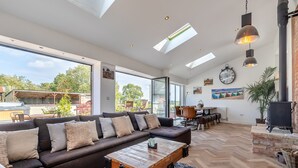 A spacious living area with a large sofa, a wooden coffee table, and a fireplace. - 5 bedroom accommodation in Ashbourne (Ashbourne)