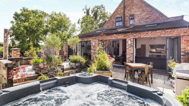 A brick house with a patio, a hot tub, and a garden. - 5 bedroom accommodation in Ashbourne (Ashbourne)