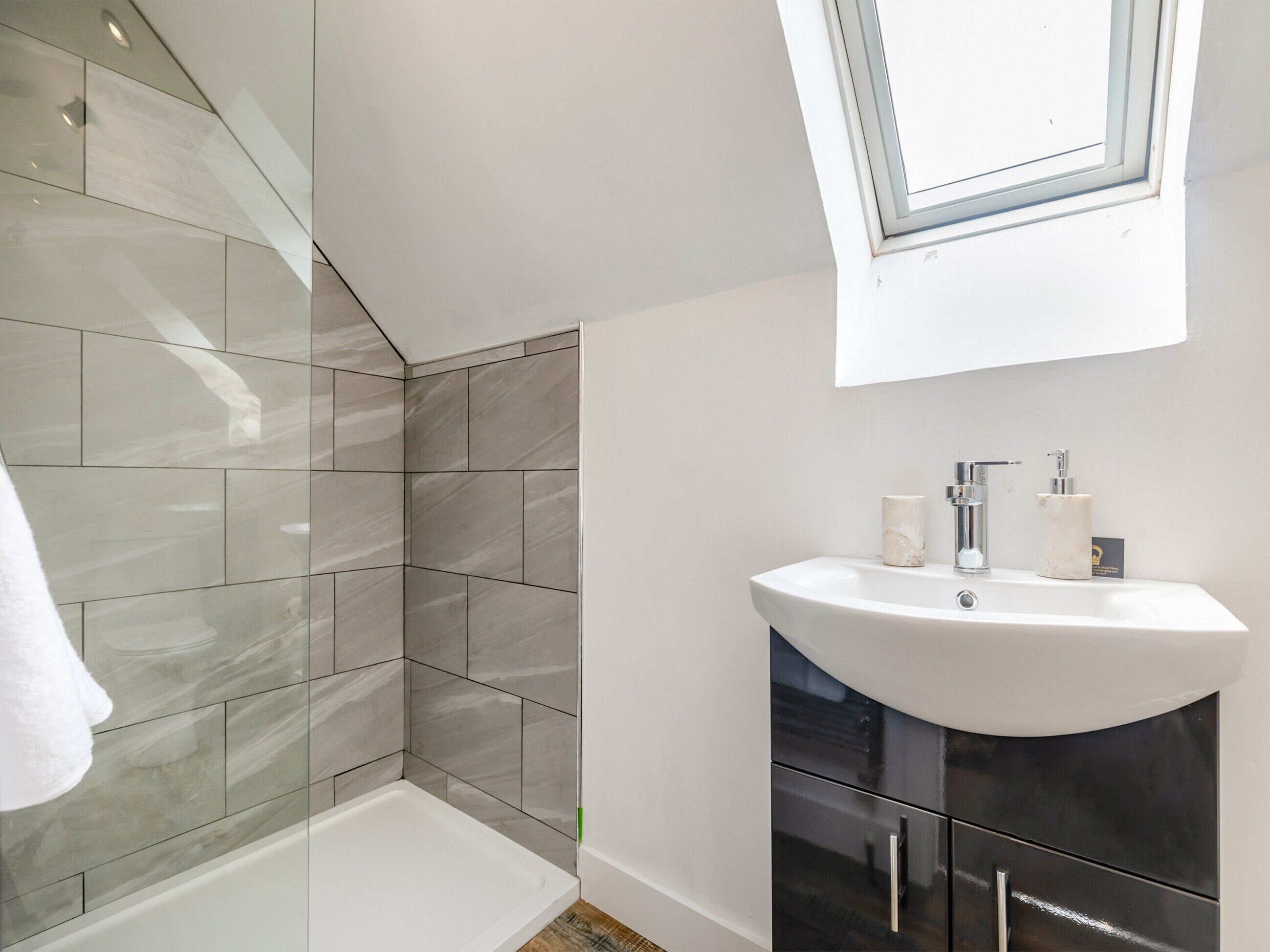 Un baño moderno con tragaluz, una bañera y un tocador con lavamanos.