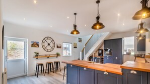 A modern kitchen with a central island, dark cabinetry, and pendant lighting. - 5 bedroom accommodation in Ashbourne (Ashbourne)