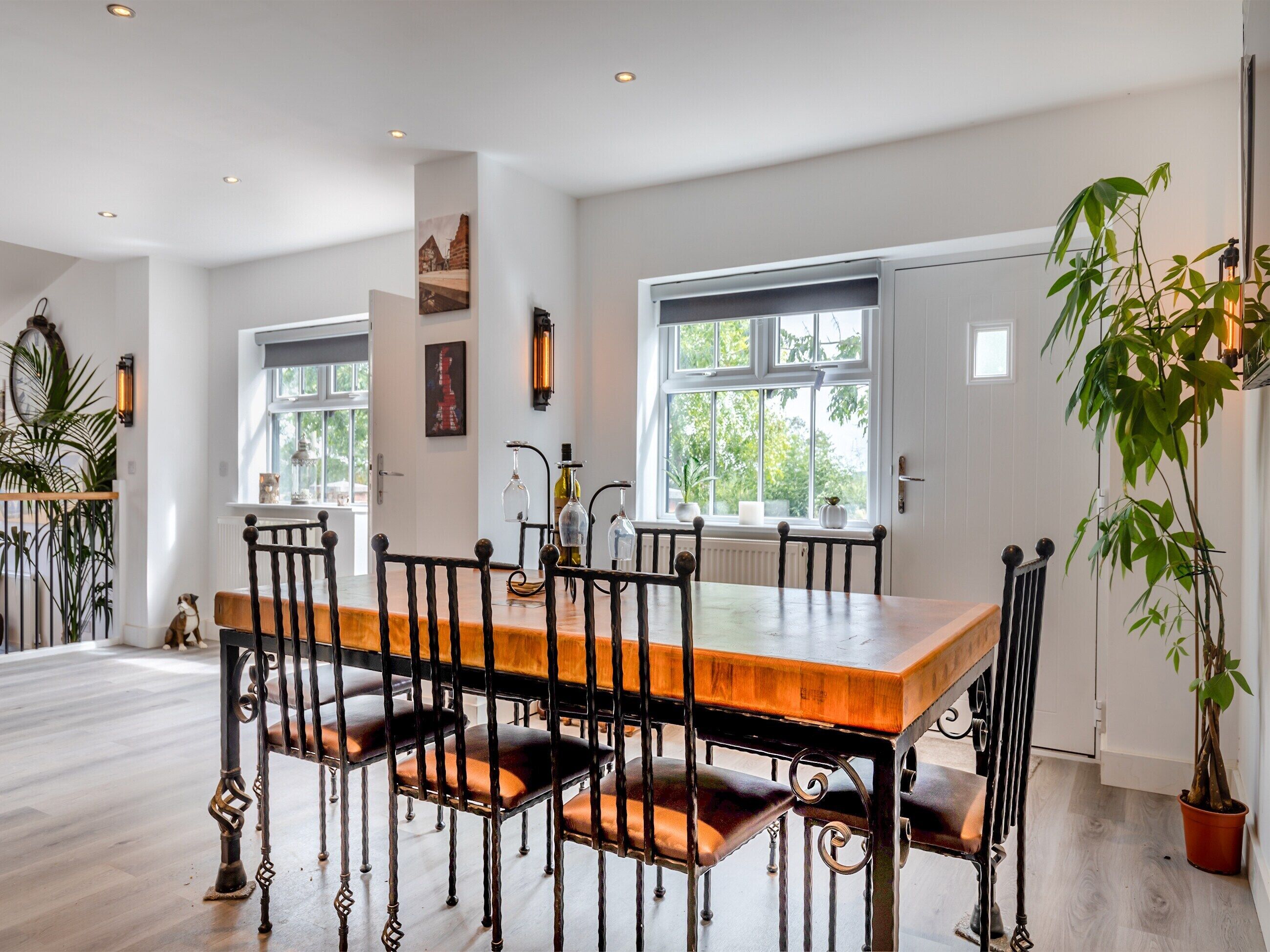 A dining area with a wooden table and chairs, a window with a view of greenery, and a radiator on the wall.