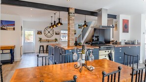 A spacious kitchen with a large island, modern appliances, and a dining area with a wooden table and chairs. - 5 bedroom accommodation in Ashbourne (Ashbourne)