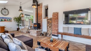 A spacious living area with a fireplace, comfortable seating, and a large clock on the wall. - 5 bedroom accommodation in Ashbourne (Ashbourne)